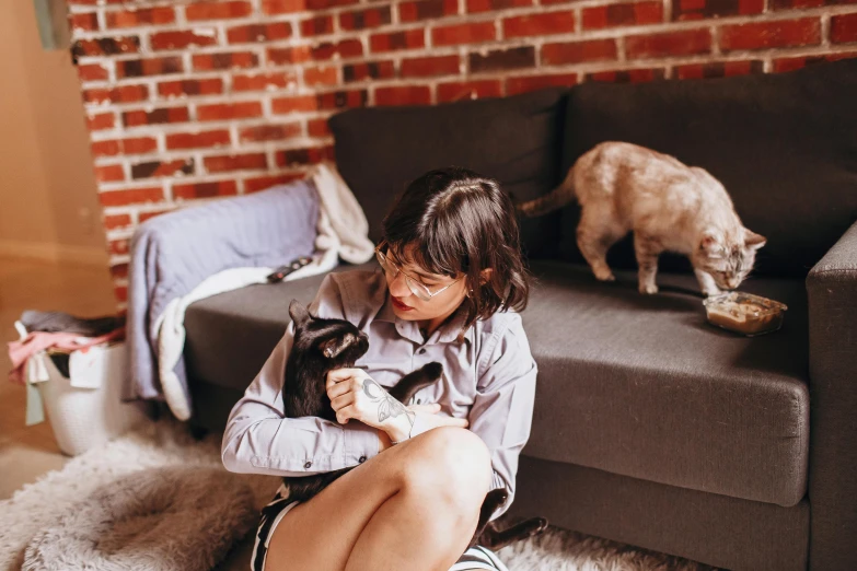 a woman holding a cat on her lap and looking at it