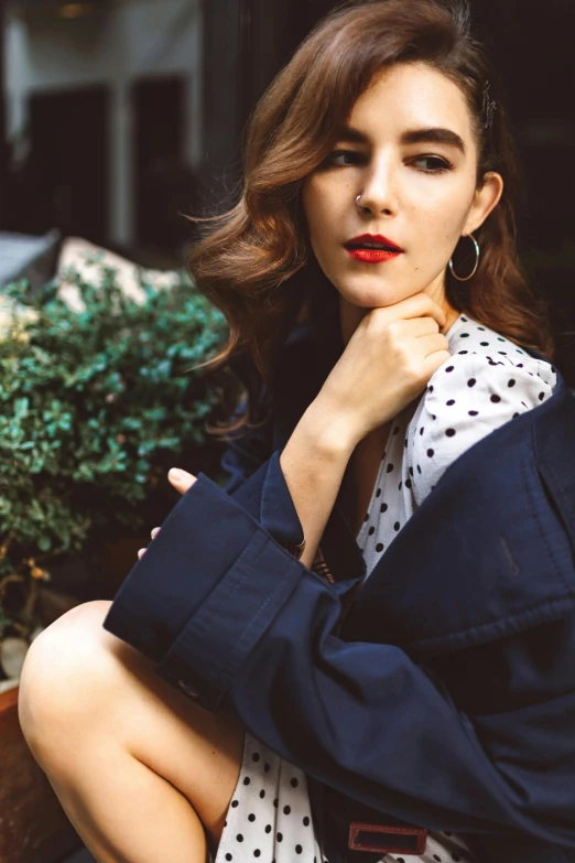 a woman with her arms crossed is leaning against the side of a planter