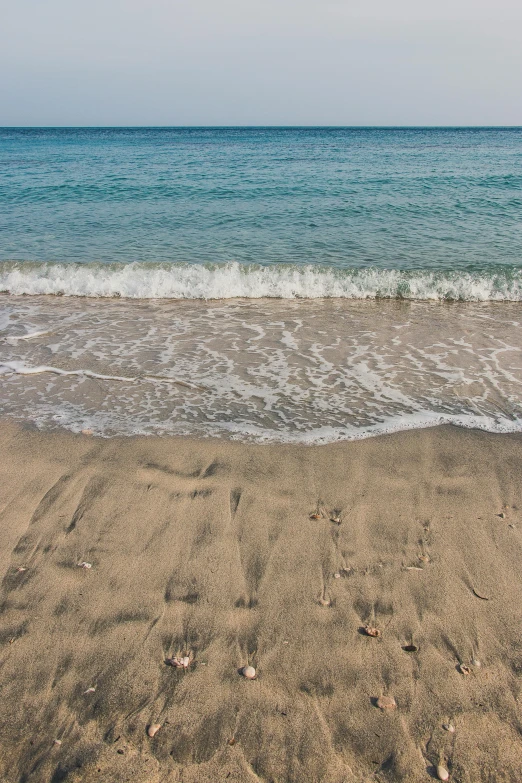 a sandy beach with water and blue sky