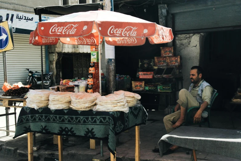 a man sitting outside of a store with a table set up