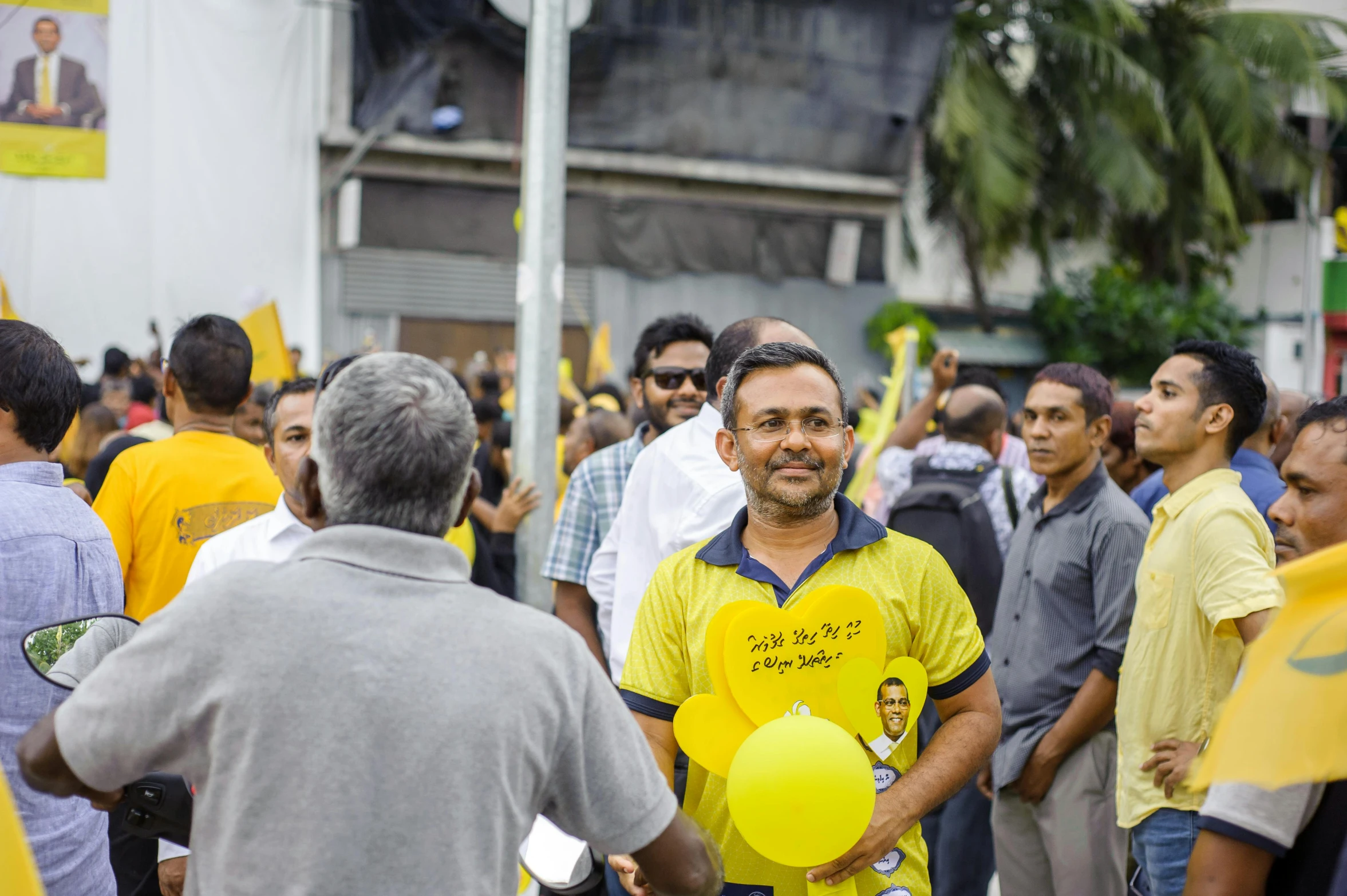 a man smiles as he holds balloons at a protest