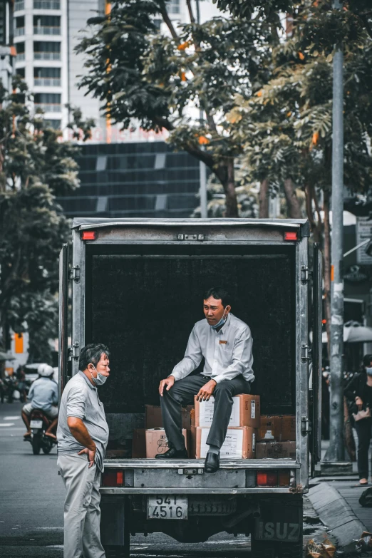 two people sitting in the back of a truck talking