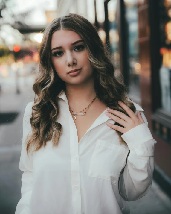 a woman posing with her hand on her hip and wearing a white shirt with long sleeves