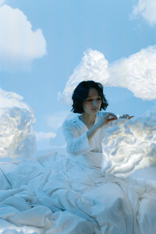 the image shows an individual sitting on a bed, with clouds over her and blue skies in background