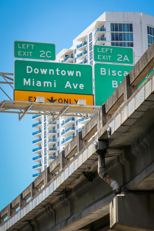 several street signs on top of a freeway bridge