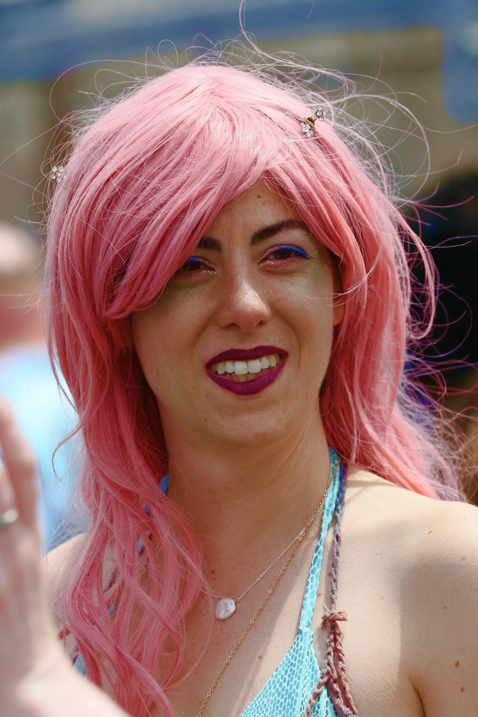 a girl with pink hair and big  smiles at the camera