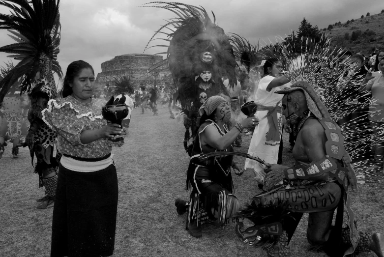 women dressed in native american clothing stand near a group of people