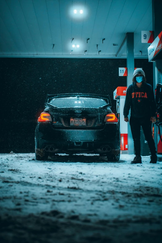 a man is standing behind the car covered with snow