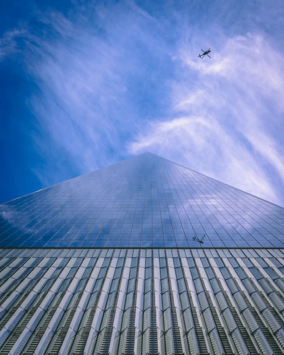 an airplane flying in the blue sky near a tall building