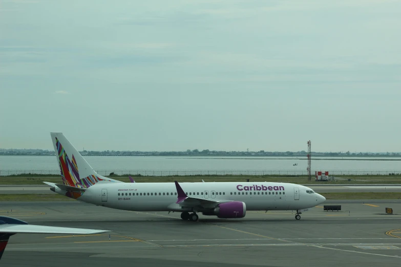 a white plane is sitting on a runway near a body of water