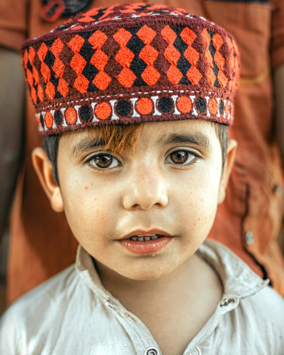 a little boy is wearing a patterned hat