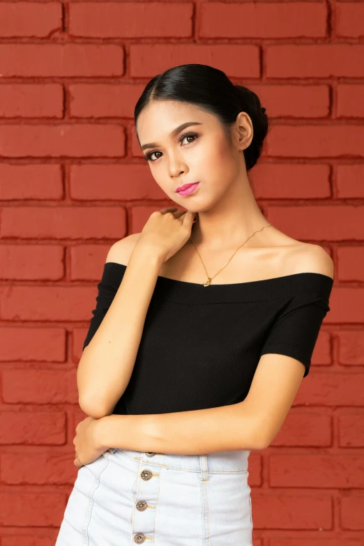 a woman in black and white poses in front of a brick wall