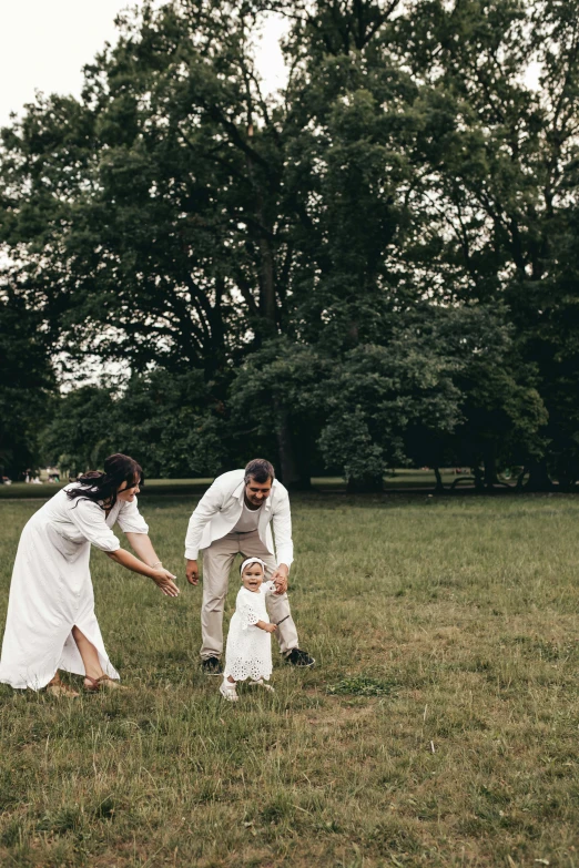 a man and woman stand in a field with a baby