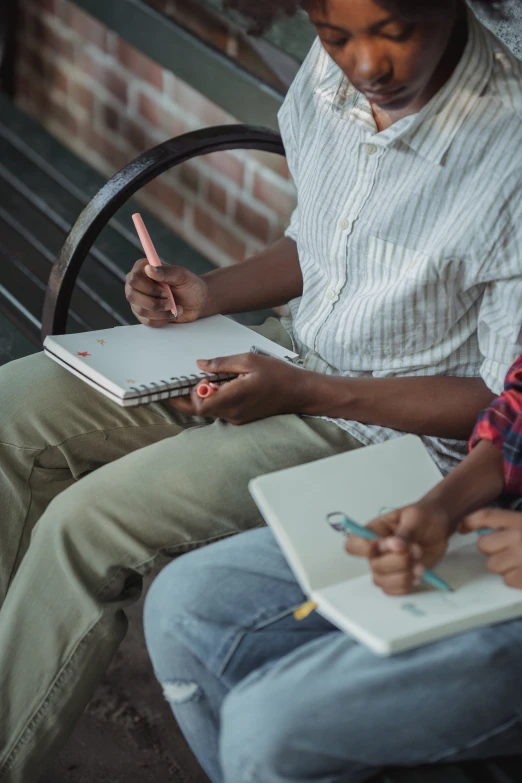 a woman writes while holding a notebook in her lap