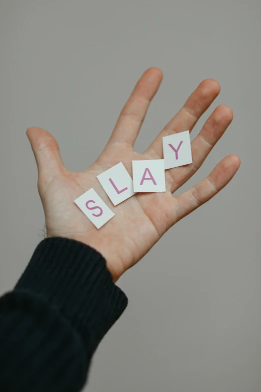 someone is holding out the word slay spelled on their palm