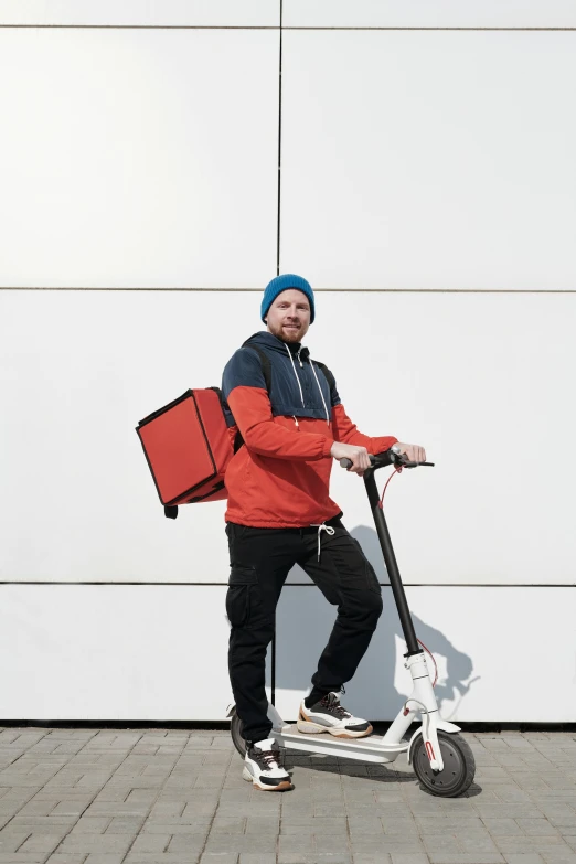 a man in an orange jacket carrying luggage on top of a scooter