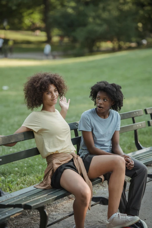 two young women sitting on a park bench