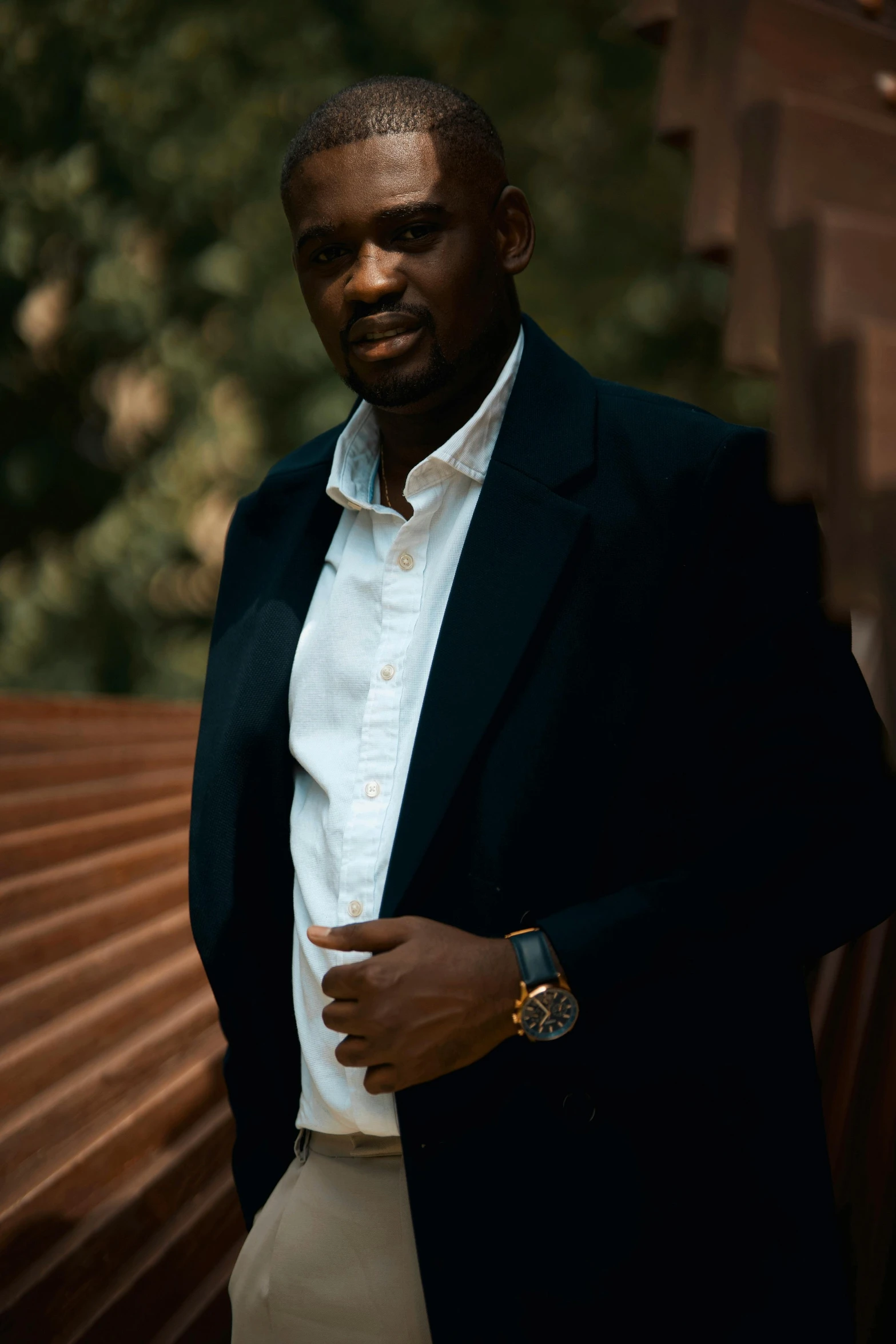 a man posing for a picture with his arm crossed and suit jacket on