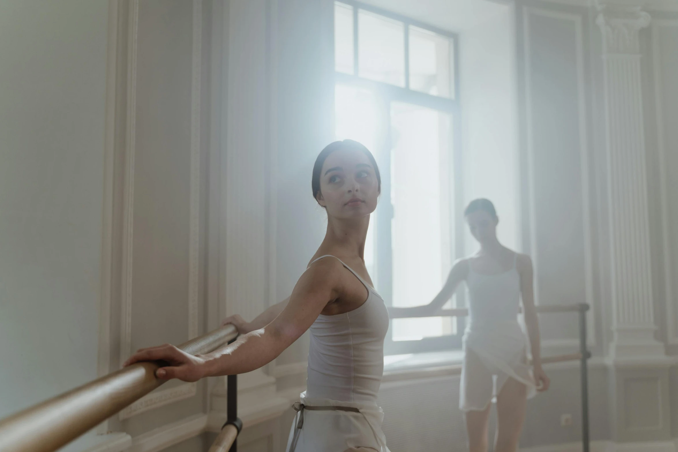 two ballet people in white tutus are next to a window