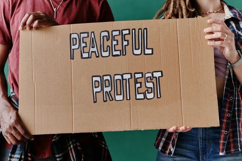 a man and woman holding a sign reading peaceful protest