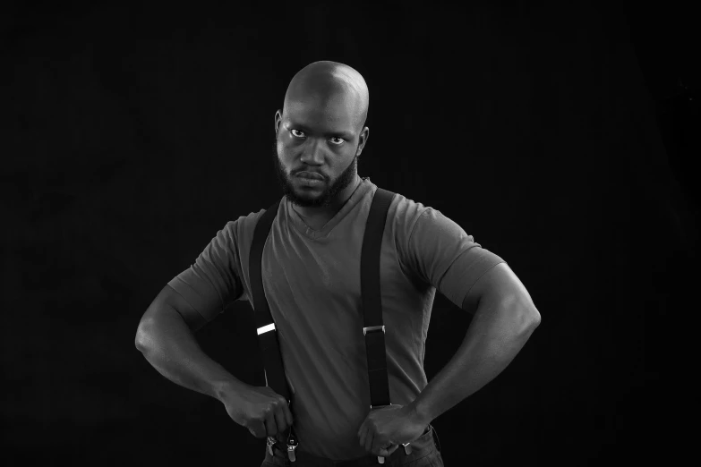 a bald man poses for the camera while holding his hands on his hips
