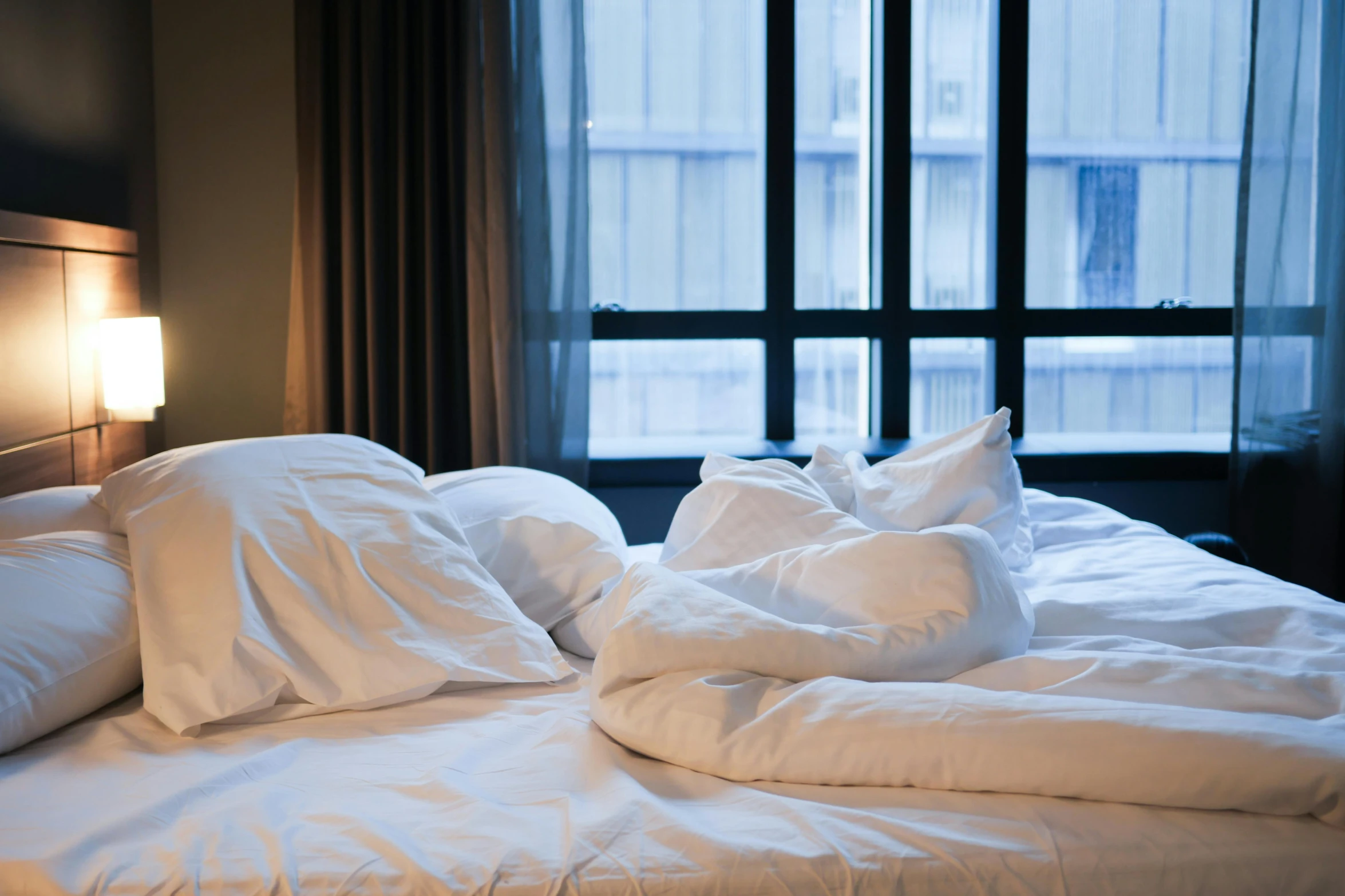 a bed topped with white pillows next to a window