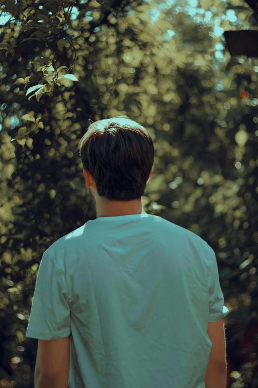 young man in front of trees stares down