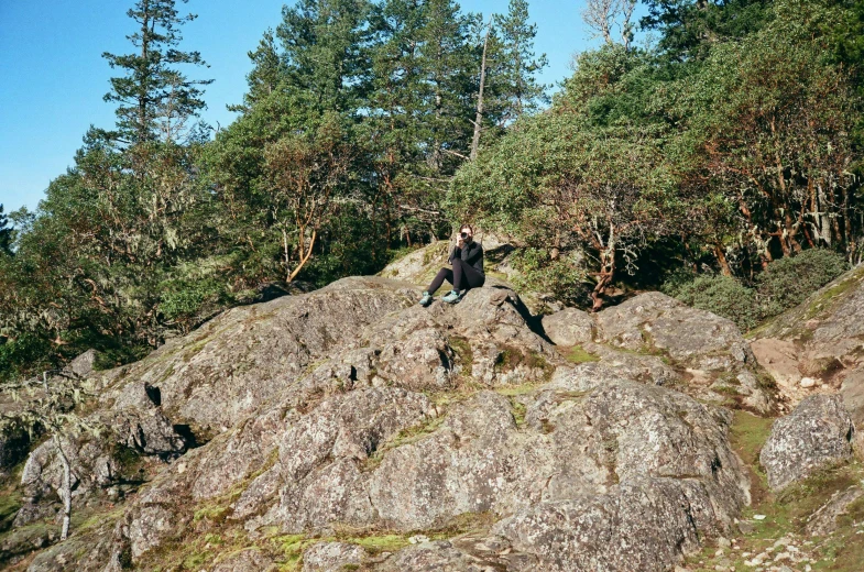 a man on top of a rock in the woods