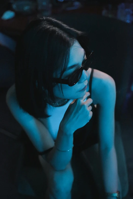 a woman wearing sunglasses sitting in the dark