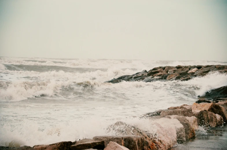 waves crashing on a rocky shoreline on a cloudy day