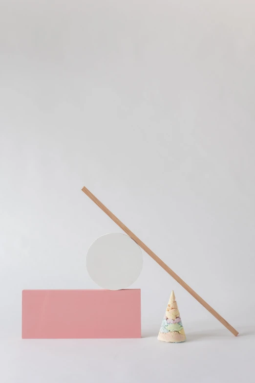 a tiny pink block and a wooden stick on a white table