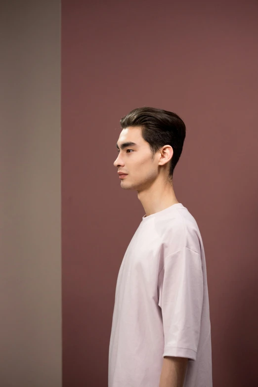 a boy is posing against a wall wearing a white t - shirt