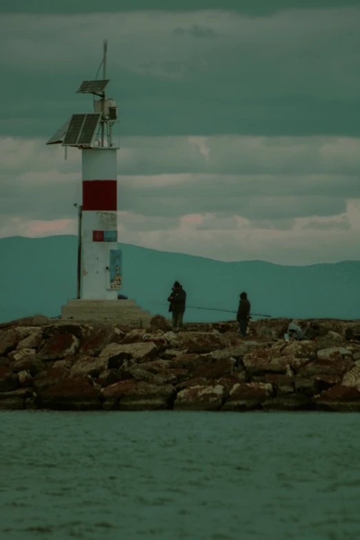 some people are near the ocean by the lighthouse