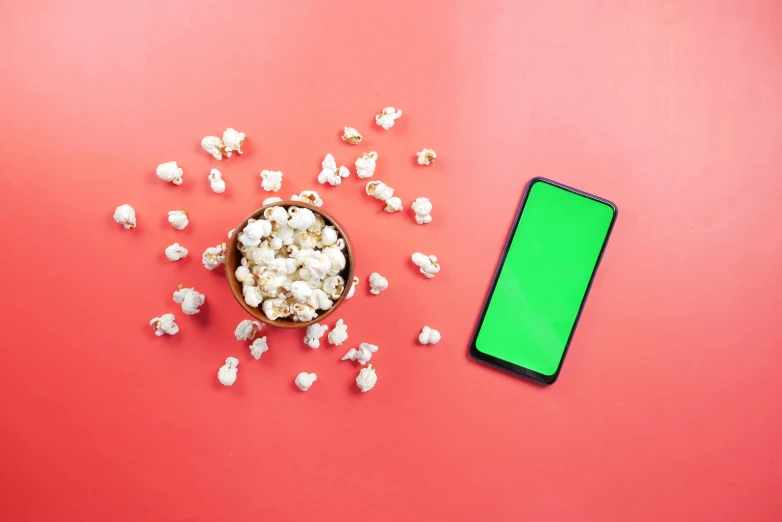 a phone and popcorn on a red background