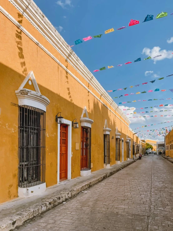 a long yellow building with colorful kites flying in the sky