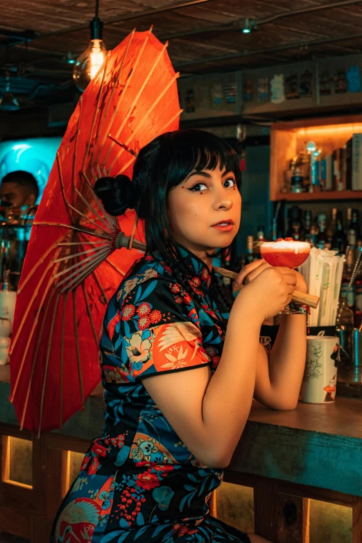 a beautiful woman sitting at a bar holding an umbrella