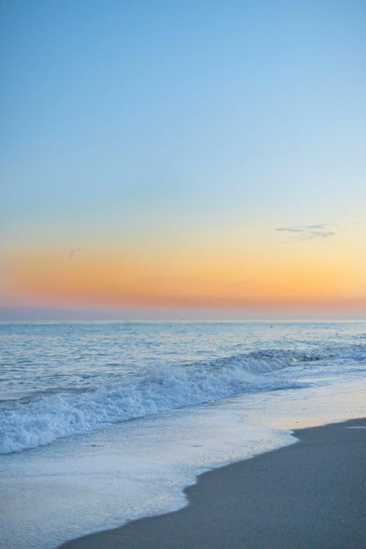 a sunset over the ocean with a small boat at the shore