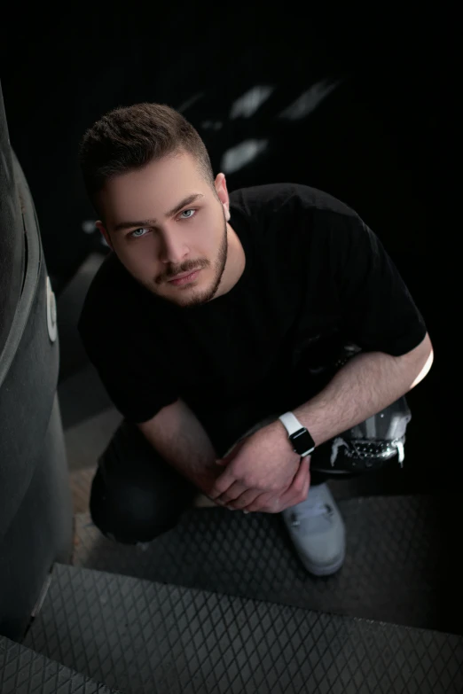 a man in a black shirt kneeling down next to a pipe