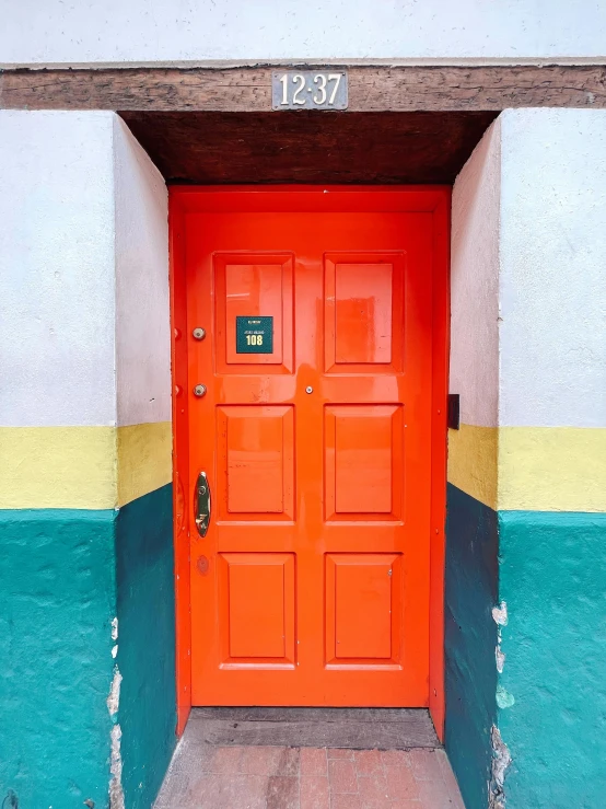 a bright orange doorway sits on a multicolored building