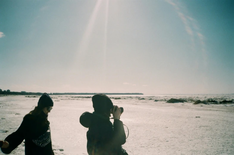 the two women are walking down the beach