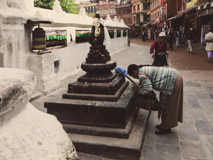 an older woman is standing by a statue