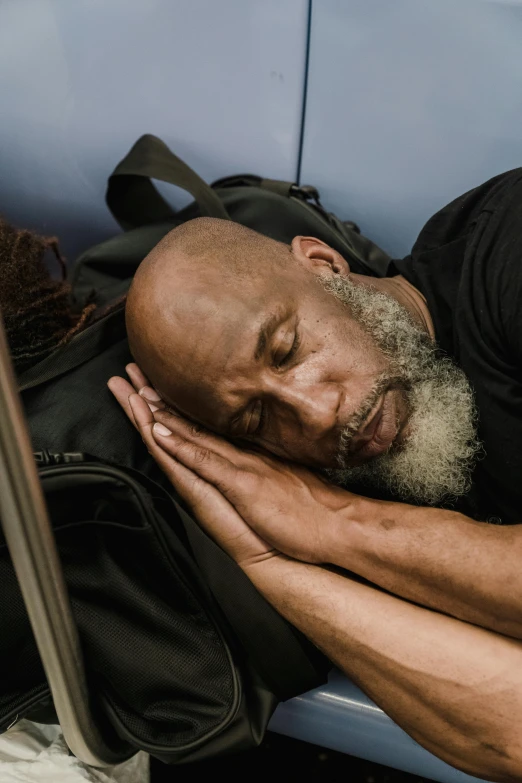 a man asleep on a train and wearing a black shirt