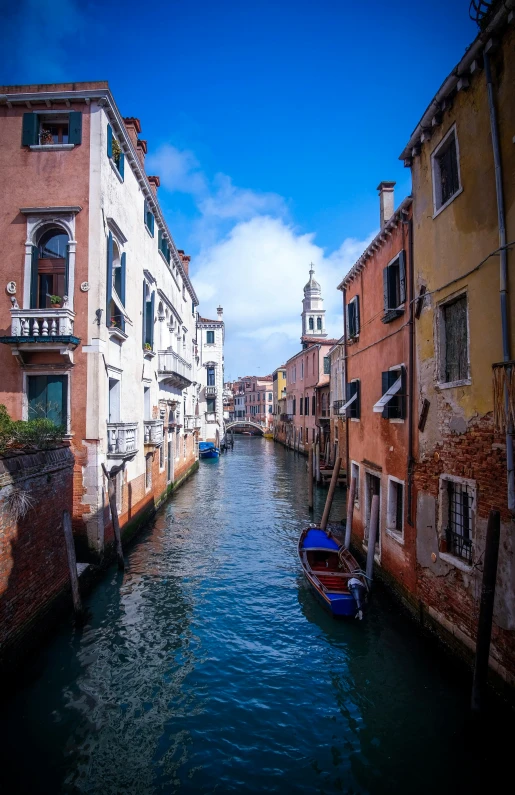 there is a narrow river with buildings and boats on it