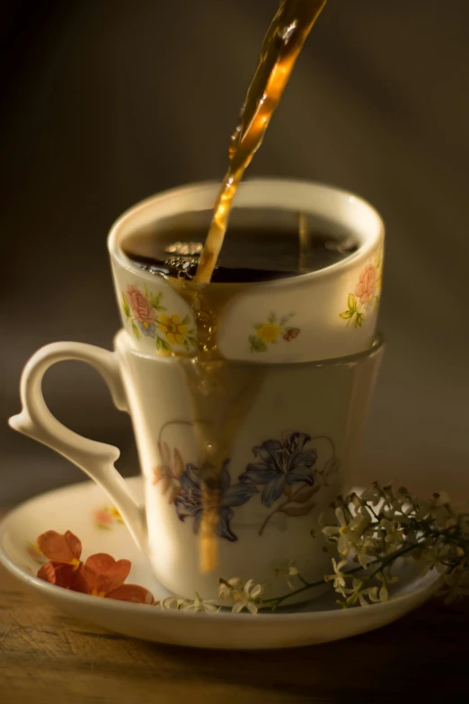 pouring liquid into a cup with some saucer and flowers on a plate