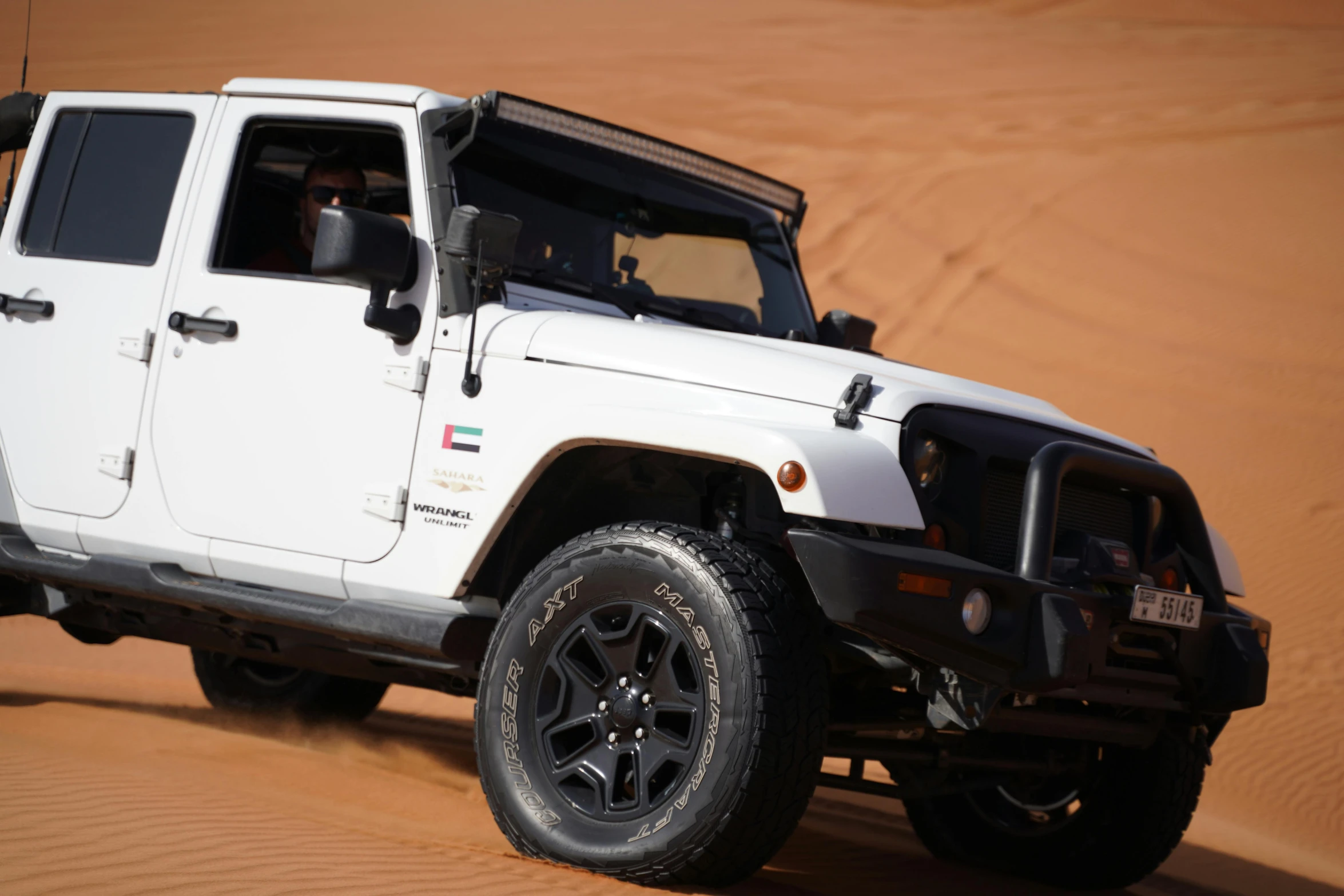 a white jeep is driving down a dirt road