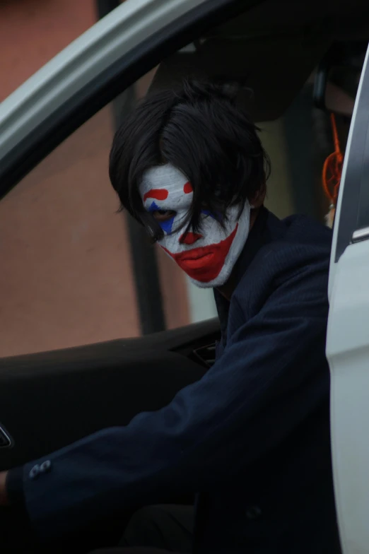 a man wearing face paint sitting in a car