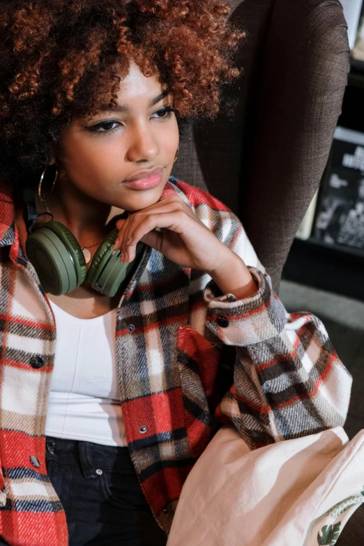 a woman in plaid shirt sitting on chair with her hands folded up