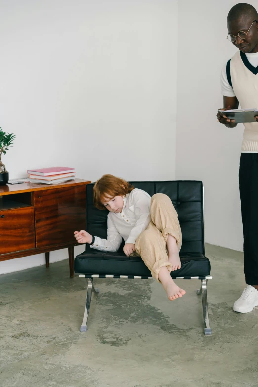 woman sitting in chair looking at cell phone next to desk with desk chair and dresser