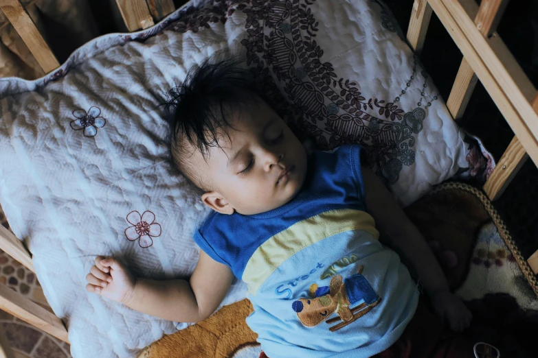 the baby boy is sleeping with his head resting on the back of a bed