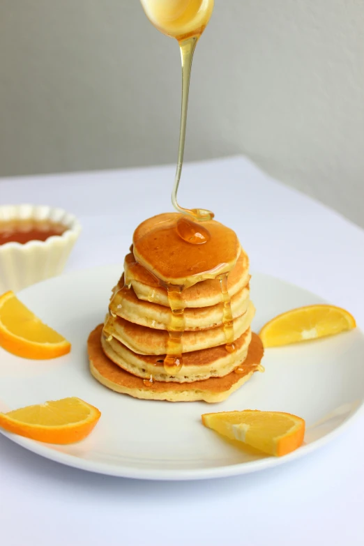 a plate with a stack of pancakes and orange slices